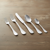 Five-piece stainless steel cutlery set with a fork, knife, and three spoons arranged diagonally on a rustic wooden tabletop.